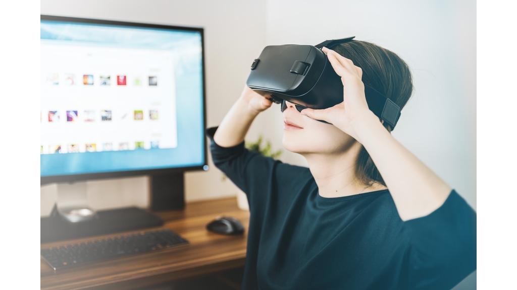 Frau mit VR Headset neben Computer